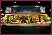 Evening ,Swamishri seated on stage amidst a garden-like setting 	