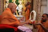Swamishri touching Thakorji's feet with devotion 