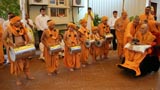 Swamishri is welcomed by children dressed as sadhus and playing dhols