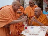 Pujya Ishwarcharan Swami ties a rakhdi on Swamishri's wrist, on behalf of all devotees