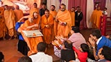 Swamishri sanctifies the decorated coconut and then tosses it back to the delighted devotees
