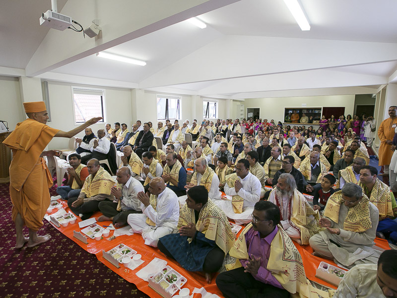 Pujya Mahant Swami blesses devotees by showering rice grains