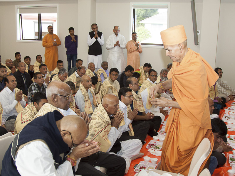 Pujya Mahant Swami blesses devotees by showering rice grains