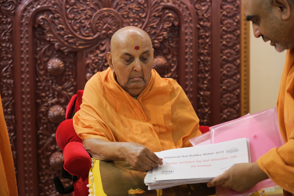 Swamishri sanctifying delegates' essays from the National Bal-Balika Mandal Shibir, Sarangpur, India