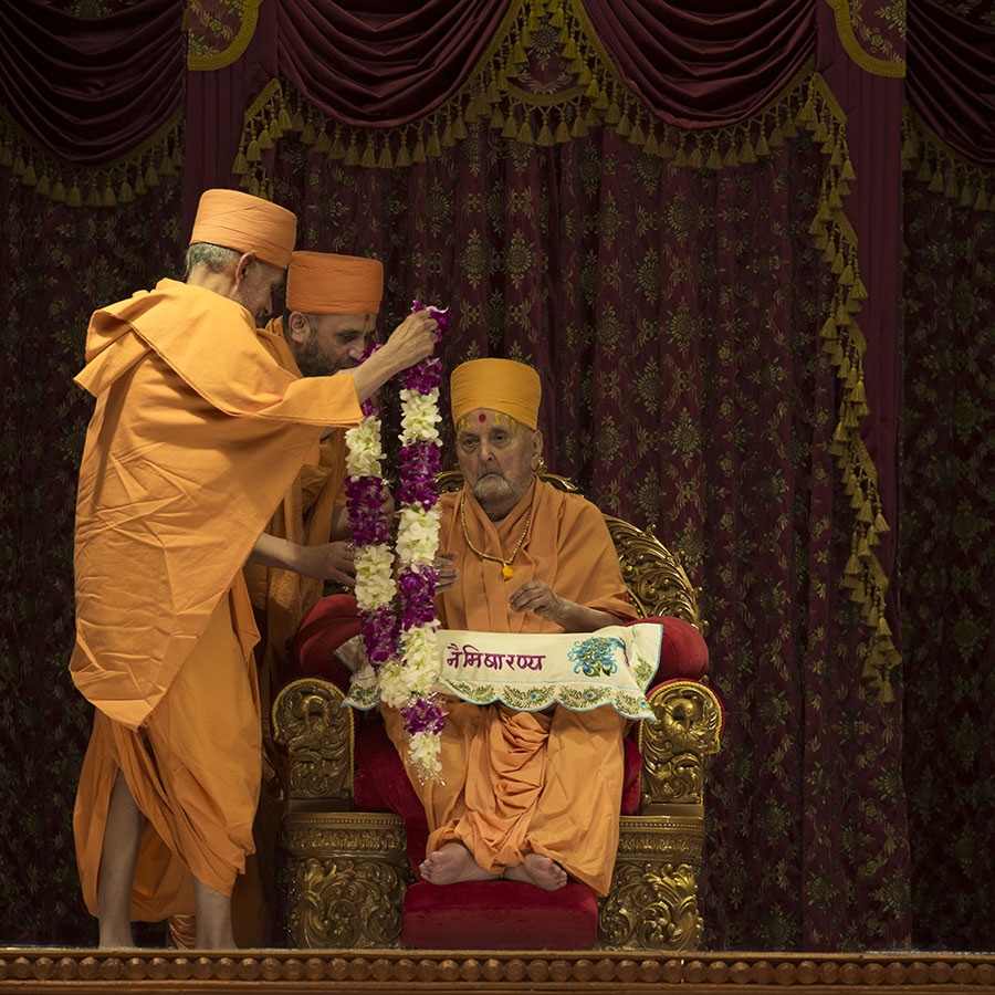 Pujya Mahant Swami honors Swamishri with a garland