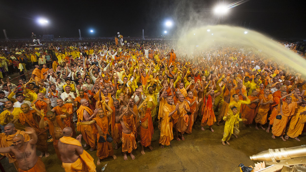 Swamishri showers sanctified colored water on sadhus and blesses them