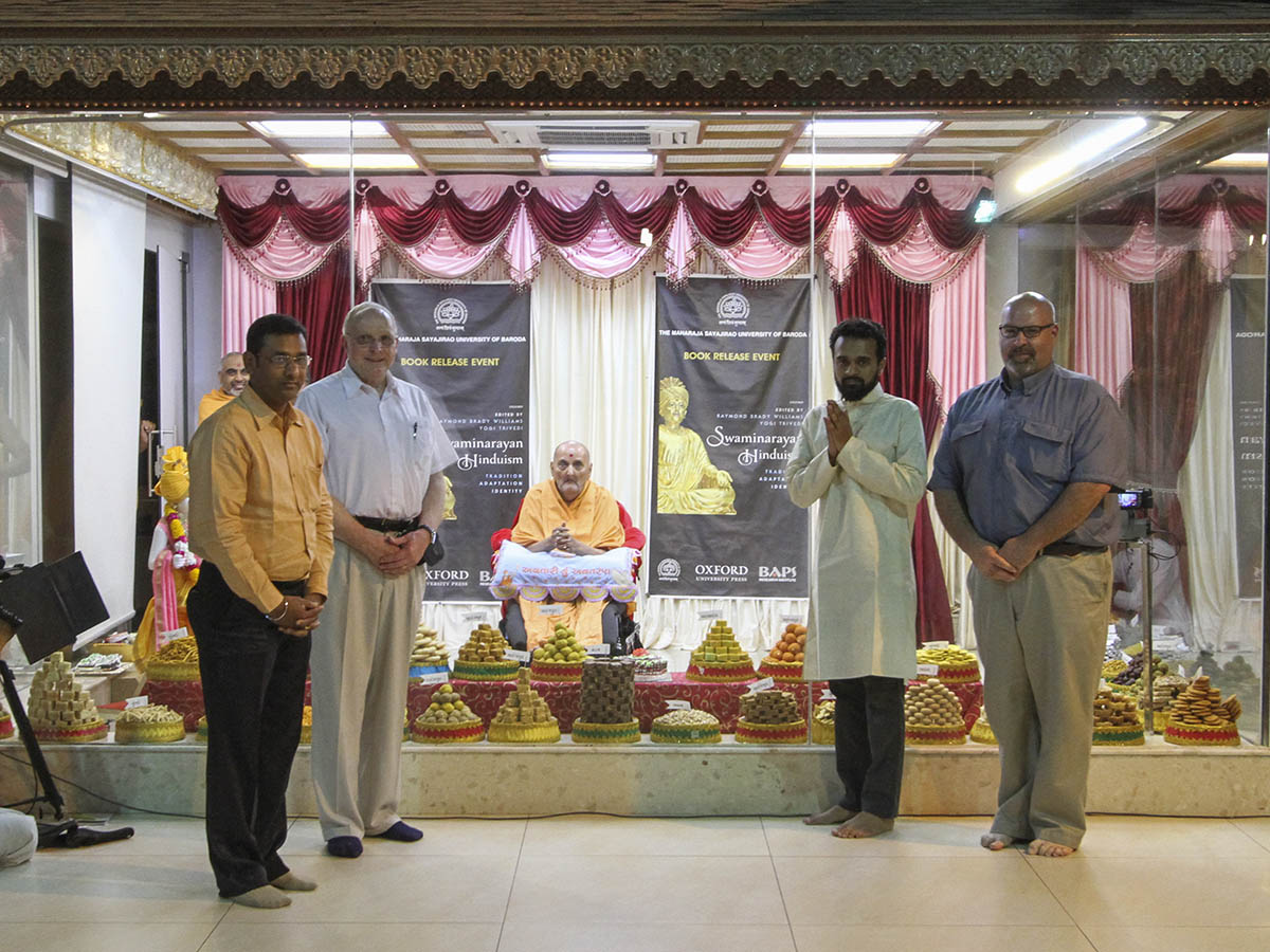 Prof. Raymond Brady Williams, Prof. Yogi Trivedi,  Pastor Matthew Manning and Nitesh Dave offer the book to Swamishri