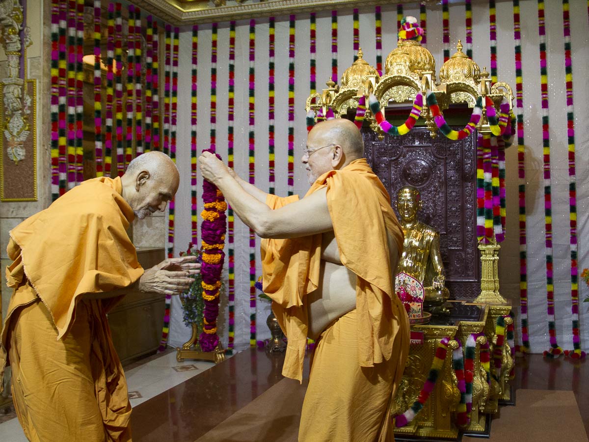 Pujya Ishwarcharan Swami welcomes Param Pujya Mahant Swami with a garland, 29 Aug 2016
