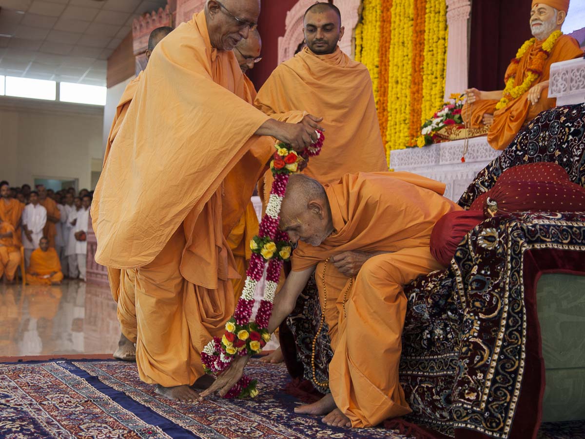 Pujya Swayamprakash Swami (Pujya Doctor Swami) honors Param Pujya Mahant Swami with a garland