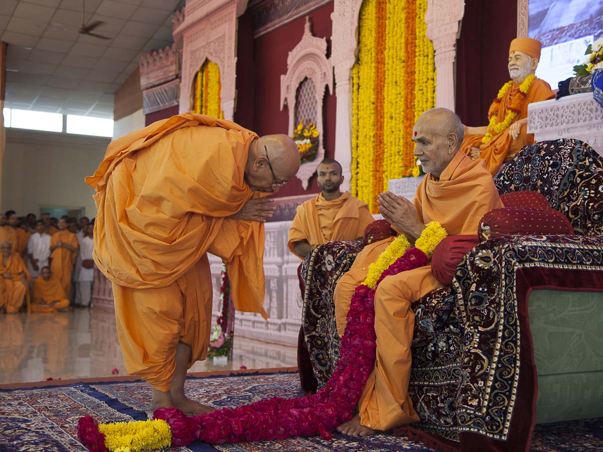 Pujya Tyagvallabh Swami honors Param Pujya Mahant Swami with a garland