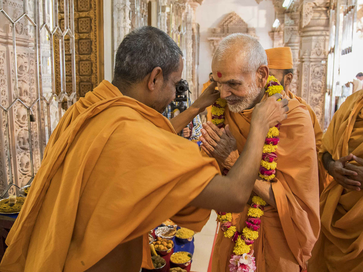 A sadhu honors Param Pujya Mahant Swami with a garland