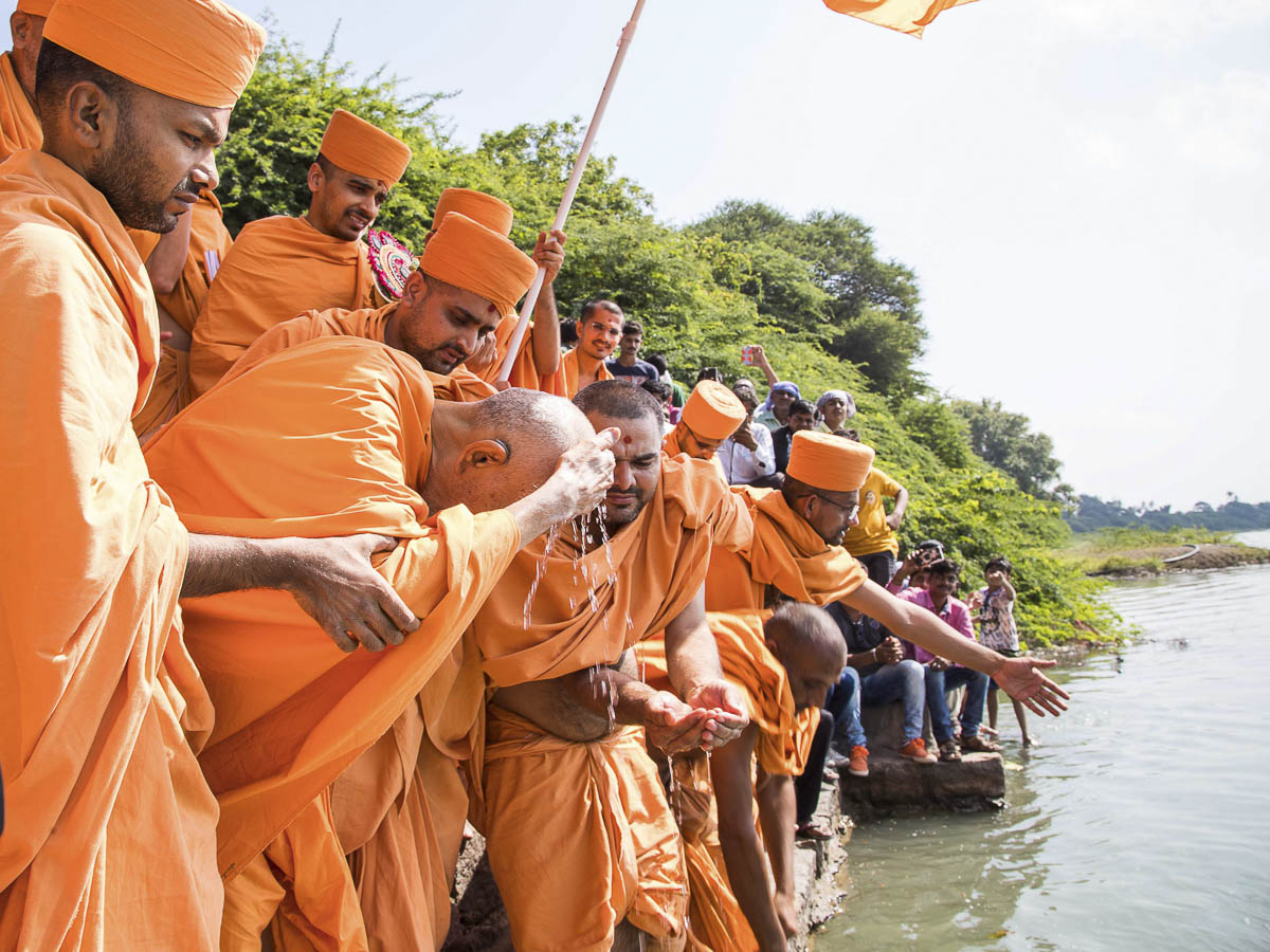 Param Pujya Mahant Swami applies the sanctified water of River Und to his head, 23 Oct 2016