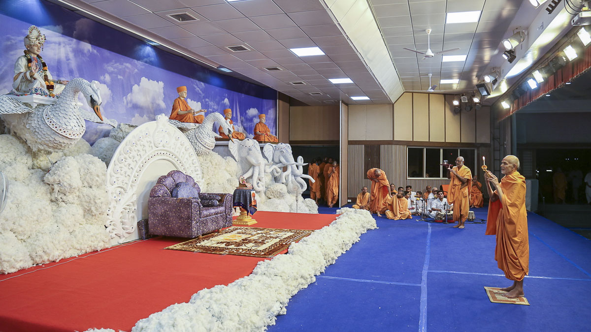 Param Pujya Mahant Swami performs arti in the evening assembly, 25 Oct 2016