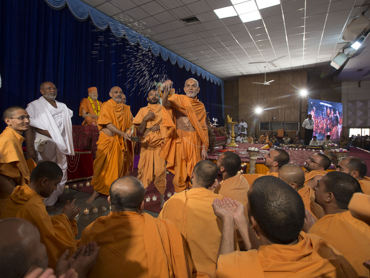 Param Pujya Mahant Swami blesses sadhus by showering rice grains