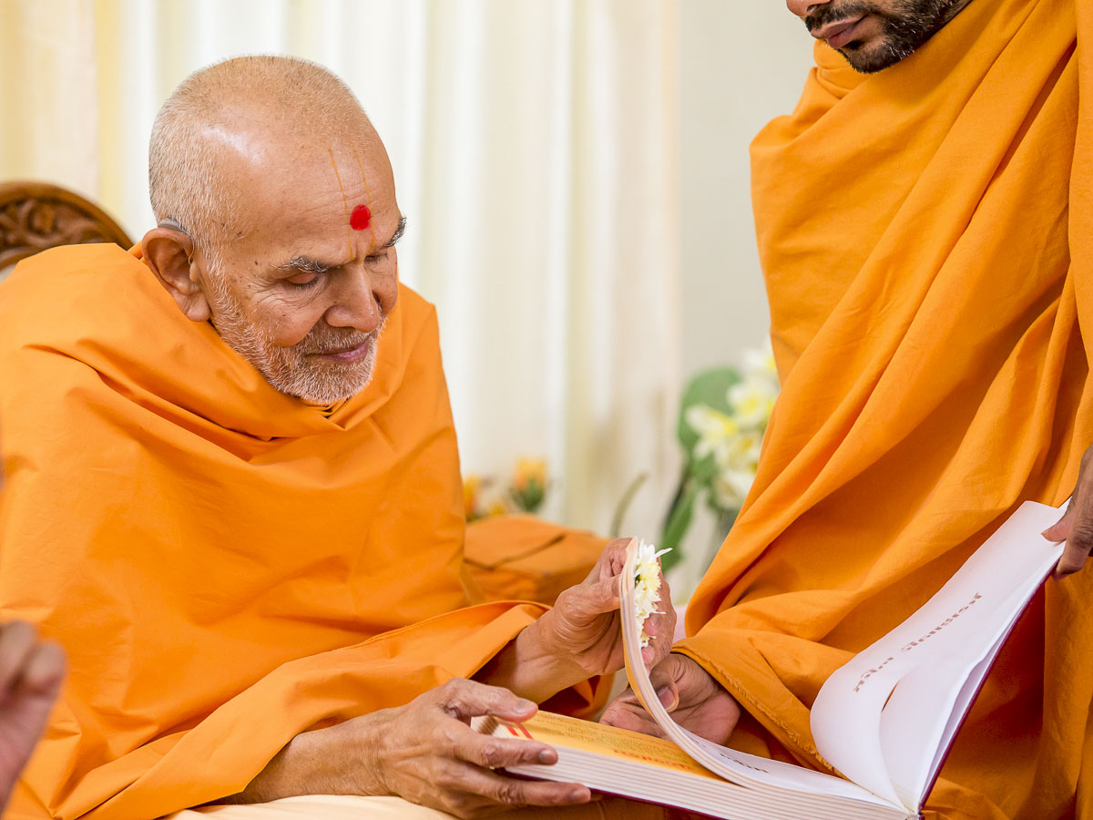 Param Pujya Mahant Swami Maharaj sanctifies a book, 24 Dec 2016