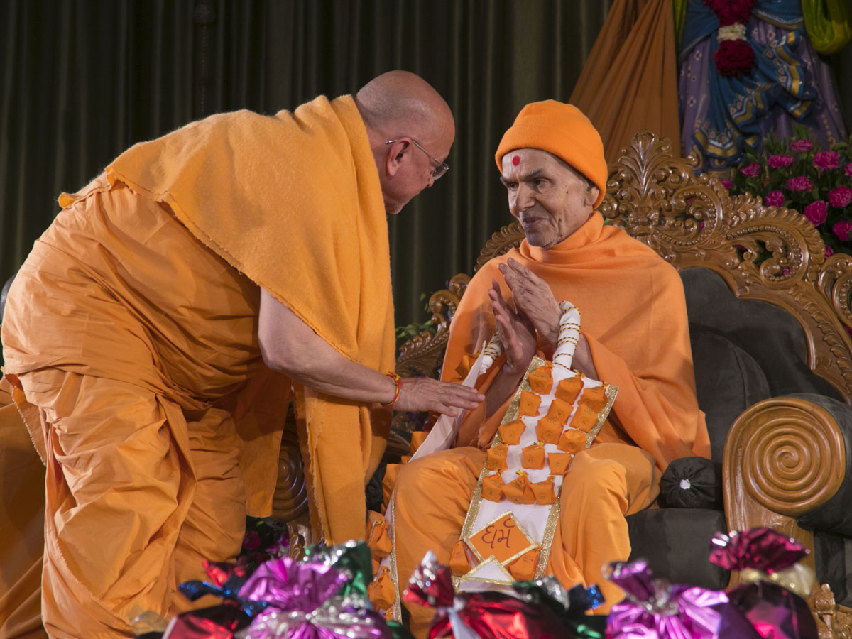 Pujya Ishwarcharan Swami honors Param Pujya Mahant Swami Maharaj with a garland 
