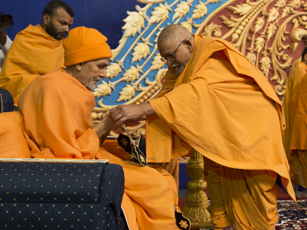 Pujya Bhaktipriya Swami honors Param Pujya Mahant Swami Maharaj with a garland