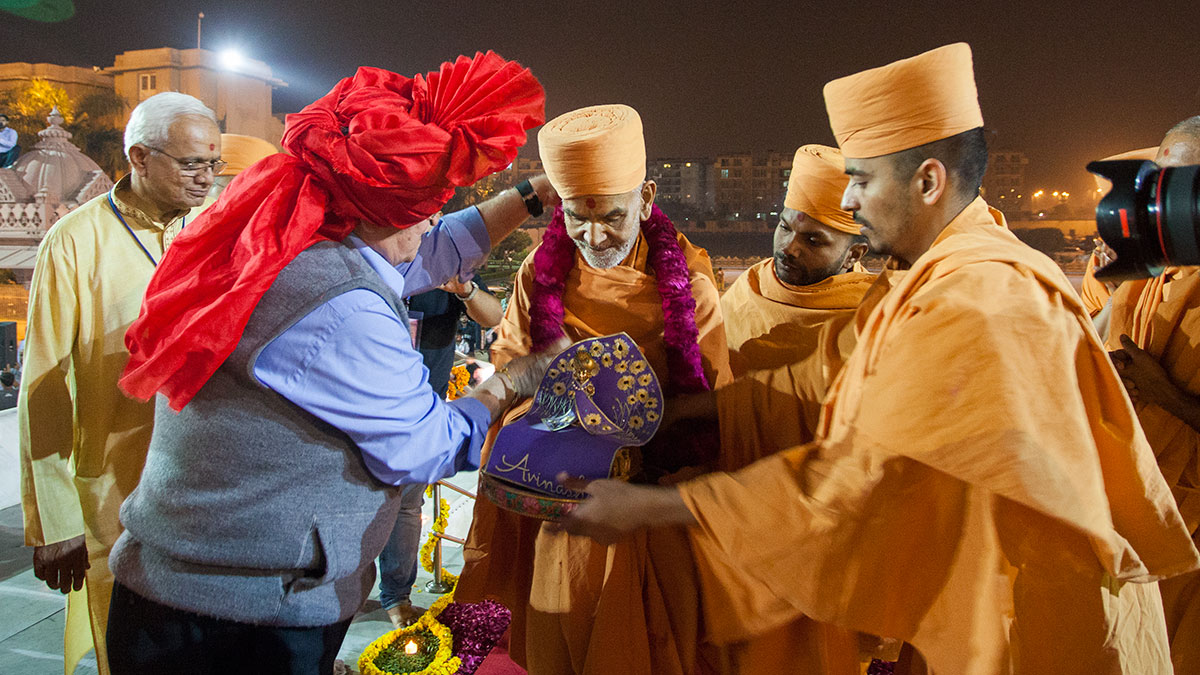 A devotee honors Param Pujya Mahant Swami Maharaj with a garland, 20 Feb 2017