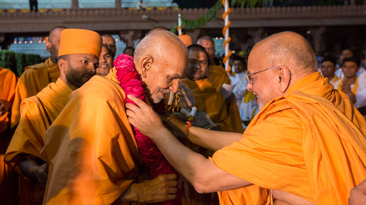 Pujya Ishwarcharan Swami honors Param Pujya Mahant Swami Maharaj with a garland, 20 Feb 2017