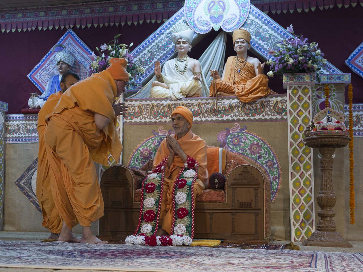 Pujya Ishwarcharan Swami honors Param Pujya Mahant Swami Maharaj with a garland, 25 Feb 2017