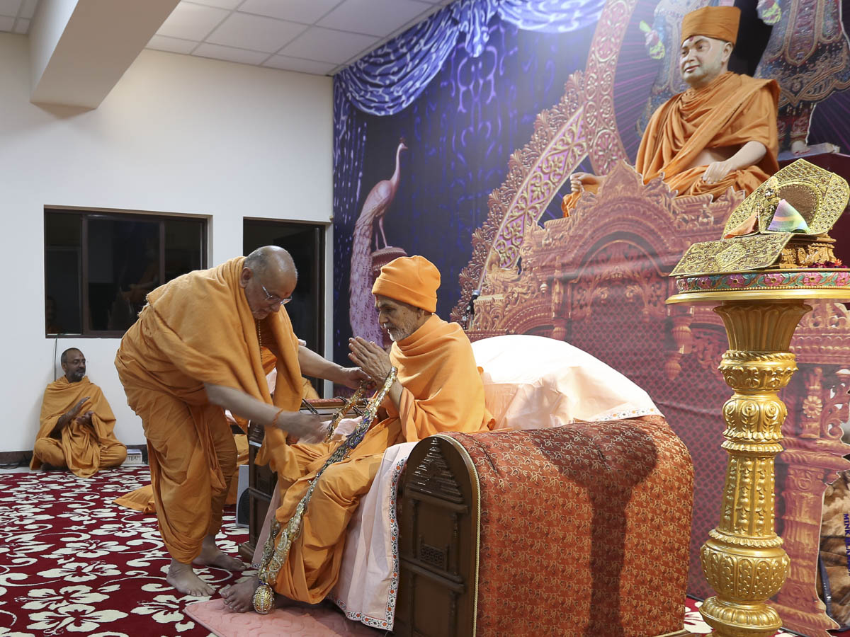 Pujya Ishwarcharan Swami honors Param Pujya Mahant Swami Maharaj with a garland