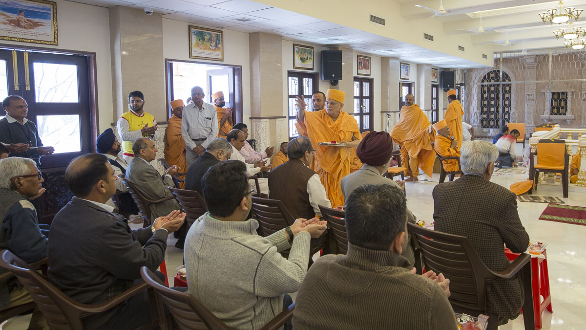 Pujya Ishwarcharan Swami blesses devotees by showering sanctified rice