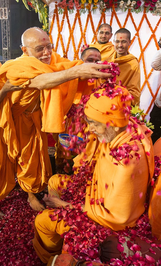 Bhaktinandan Swami showers flower petals on Param Pujya Mahant Swami Maharaj, 3 March 2017