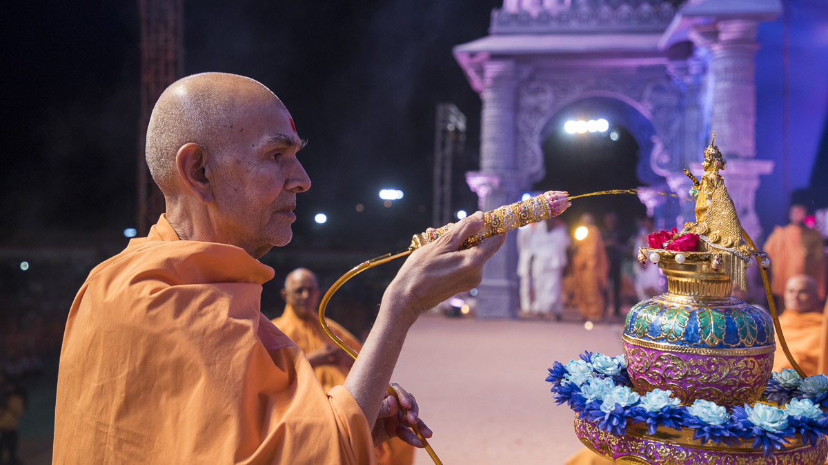 Param Pujya Mahant Swami Maharaj sprays saffron-scented water on Shri Harikrishna Maharaj