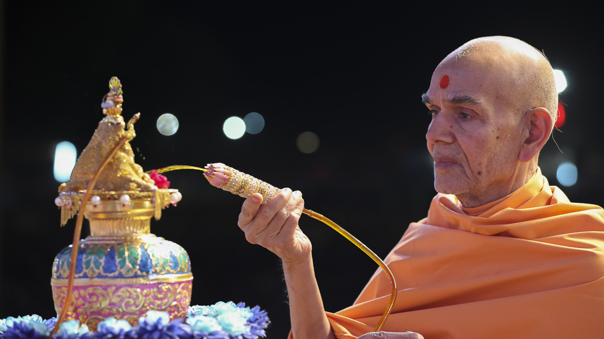 Param Pujya Mahant Swami Maharaj sprays saffron-scented water on Shri Harikrishna Maharaj