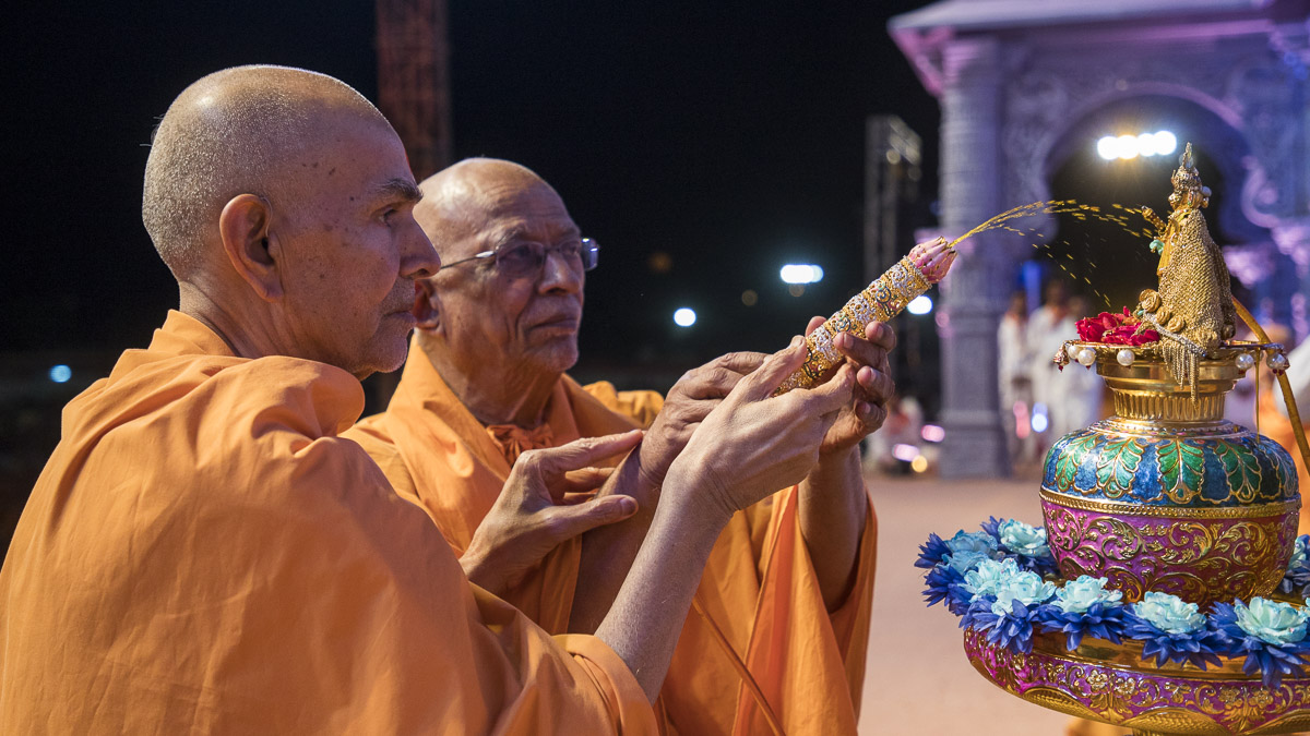 Param Pujya Mahant Swami Maharaj and Pujya Doctor Swami spray saffron-scented water on Shri Harikrishna Maharaj