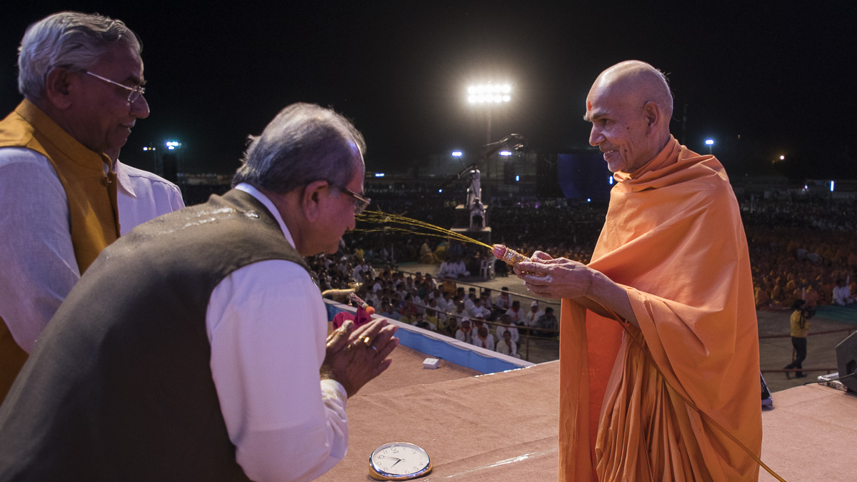 Param Pujya Mahant Swami Maharaj showers sanctified saffron-scented water on dignitaries