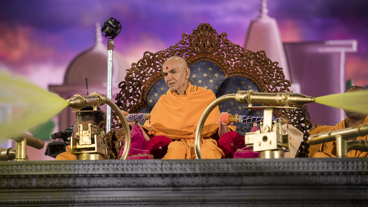 Param Pujya Mahant Swami Maharaj showers sanctified saffron-scented water on devotees