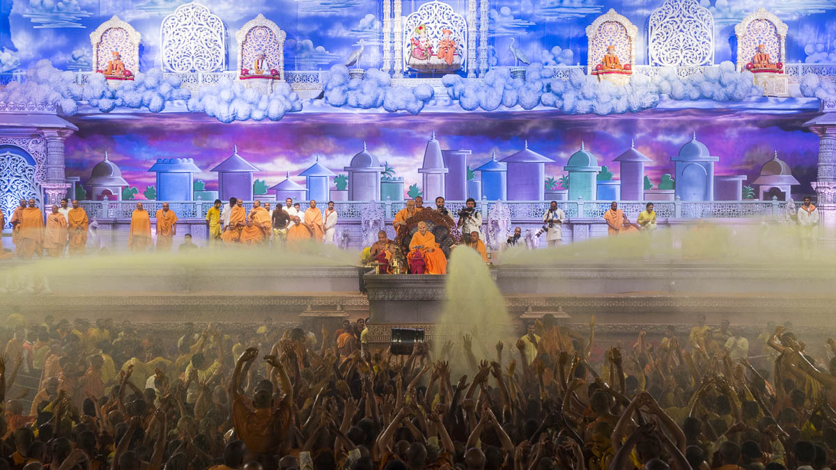 Param Pujya Mahant Swami Maharaj showers sanctified saffron-scented water on sadhus