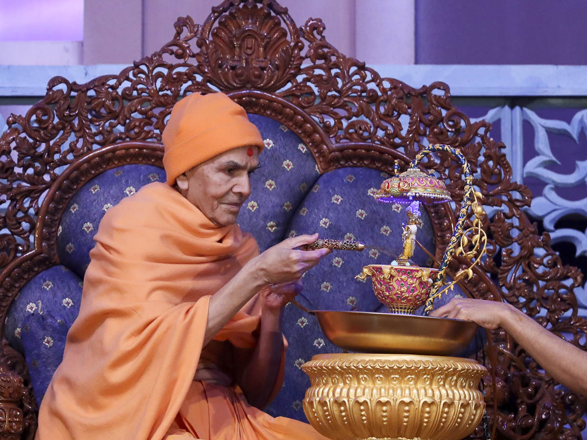 Param Pujya Mahant Swami Maharaj sprays saffron-scented water on Shri Harikrishna Maharaj, 11 March 2017