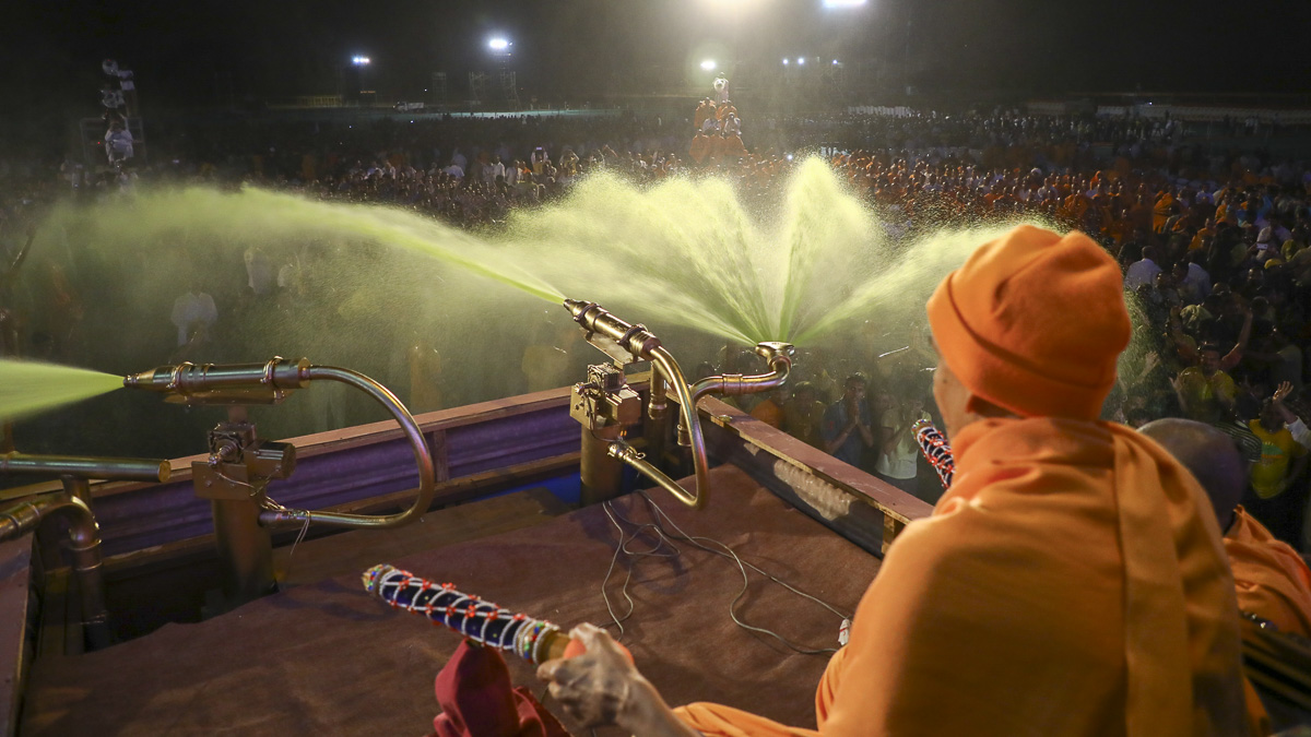Param Pujya Mahant Swami Maharaj showers sanctified saffron-scented water on volunteers, 11 March 2017