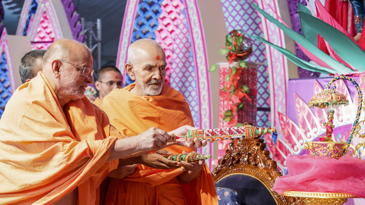 Param Pujya Mahant Swami Maharaj and Pujya Ishwarcharan Swami spray saffron-scented water on Shri Harikrishna Maharaj, 28 Mar 2017
