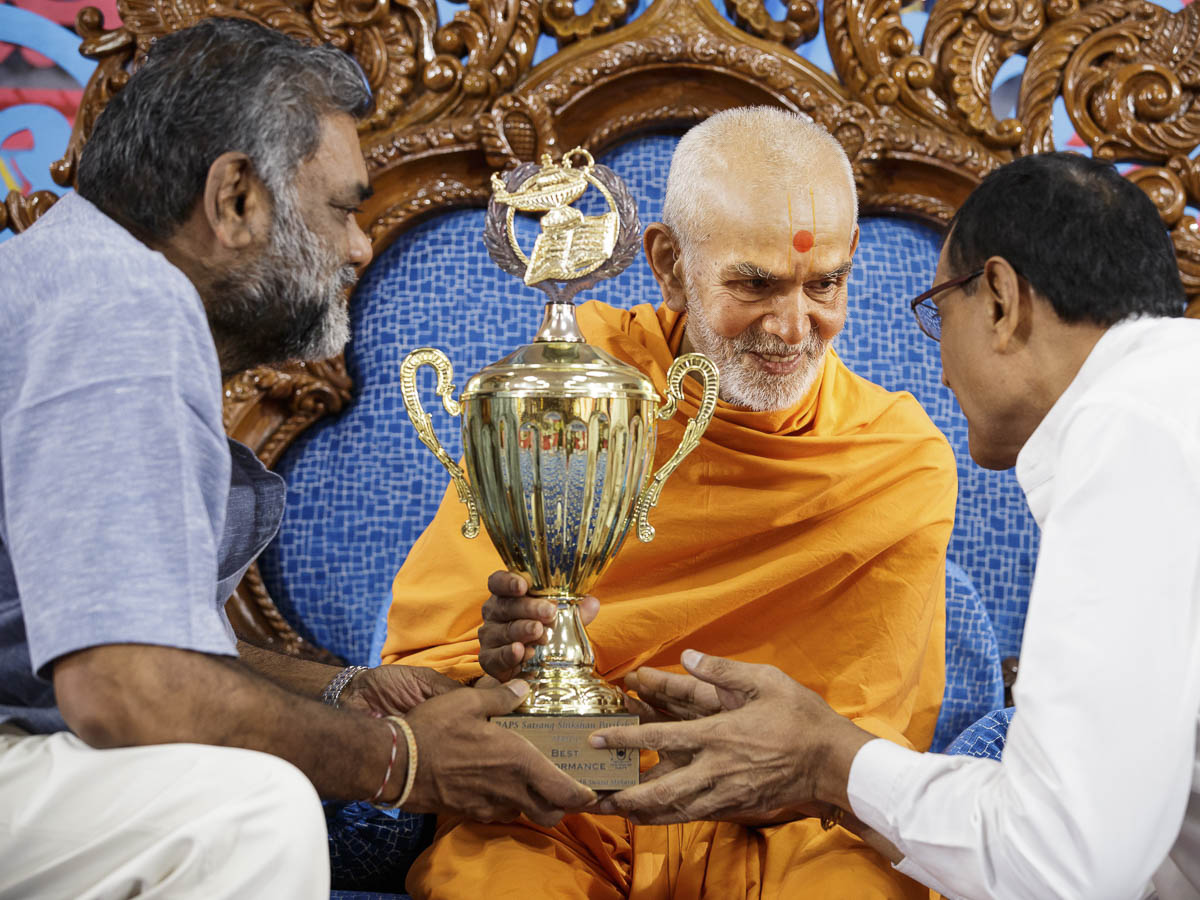 Swamishri presents a Satsang Exam award to a devotee, 30 March 2017