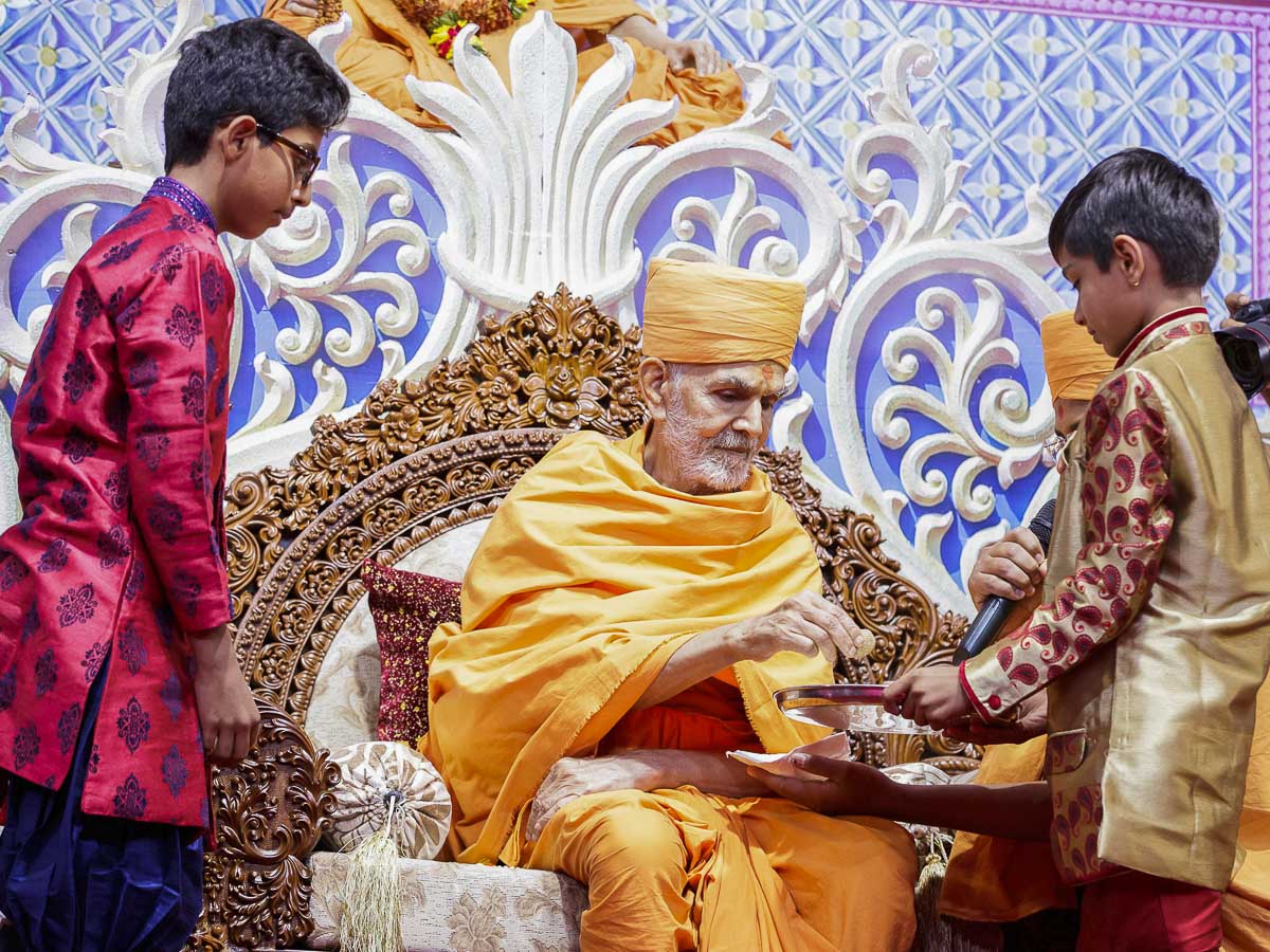 Swamishri gives prasad to a child, 7 Apr 2017