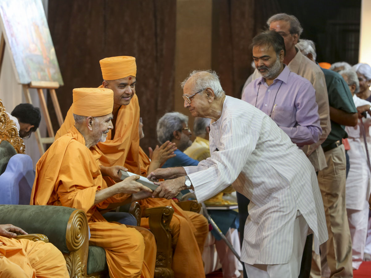HH Mahant Swami Maharaj presents books to invited guests 