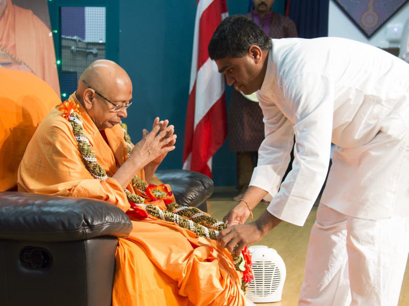 A devotee honors Pujya Tyagvallabh Swami with a garland
