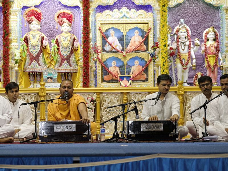 A sadhu and youths sing kirtans