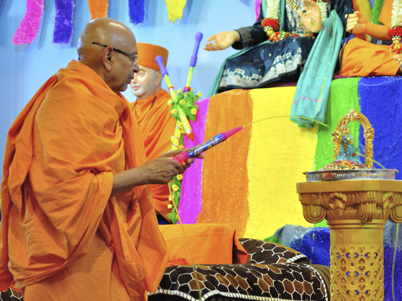 Pujya Tyagvallabh Swami sprays saffron-scented water on Shri Harikrishna Maharaj