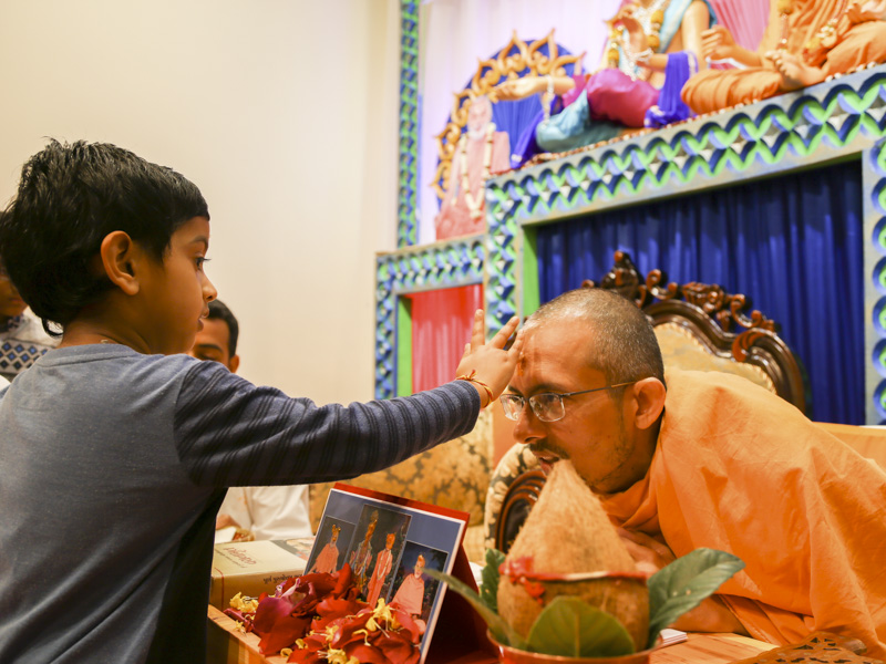A child applies chandlo to Priyaswarup Swami