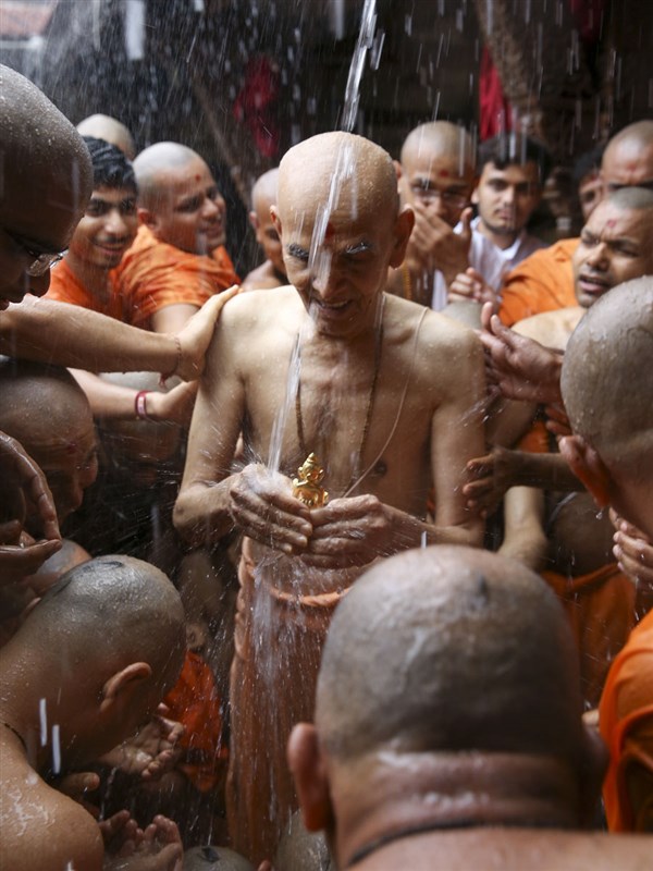Swamishri bathes Shri Harikrishna Maharaj in the first rain of the monsoon season, 8 Jun 2017