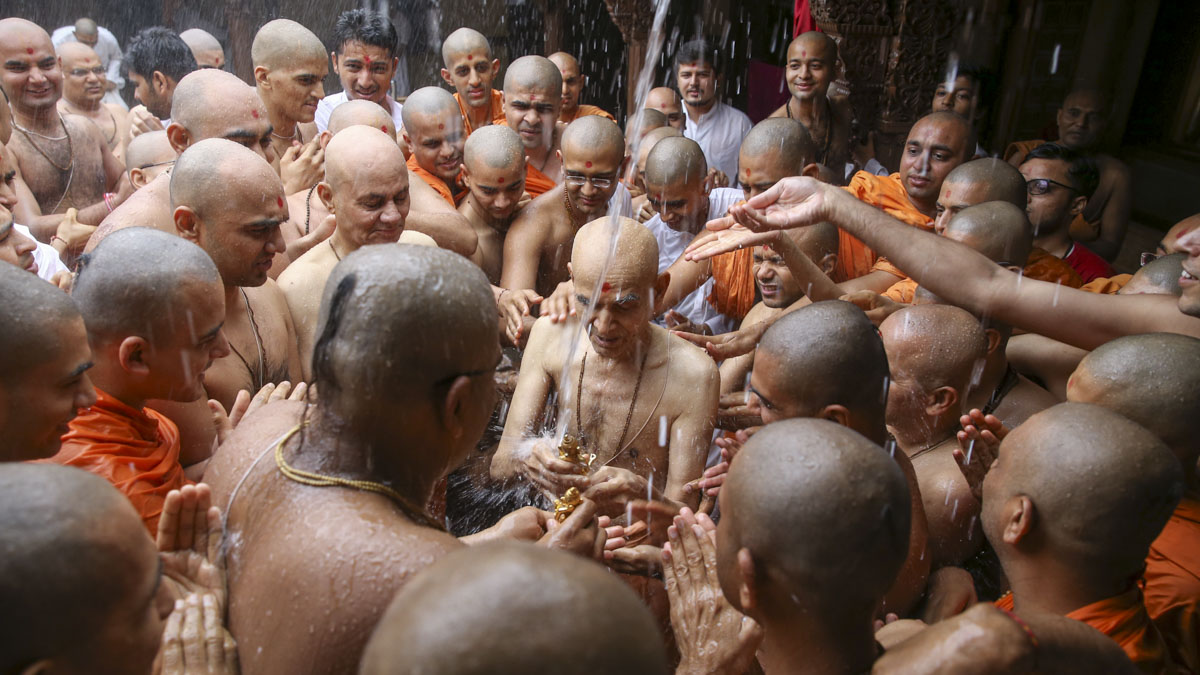 Swamishri bathes Shri Harikrishna Maharaj in the first rain of the monsoon season, 8 Jun 2017