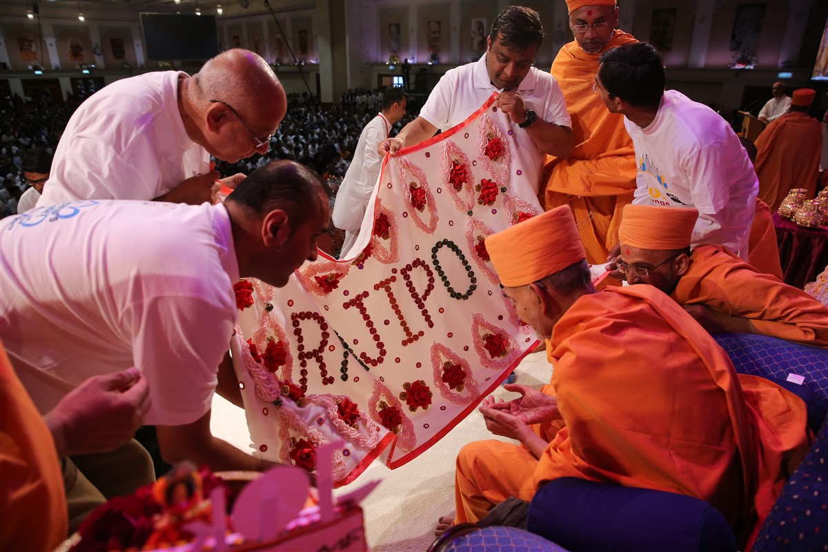 Representative volunteers offer Swamishri a decorative shawl