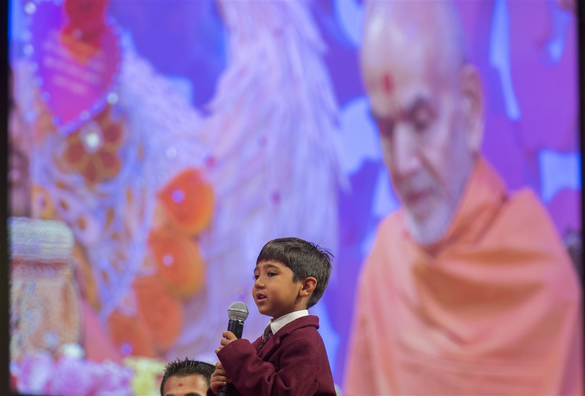 A young pupil from The Swaminarayan School presents in Swamishri's puja
