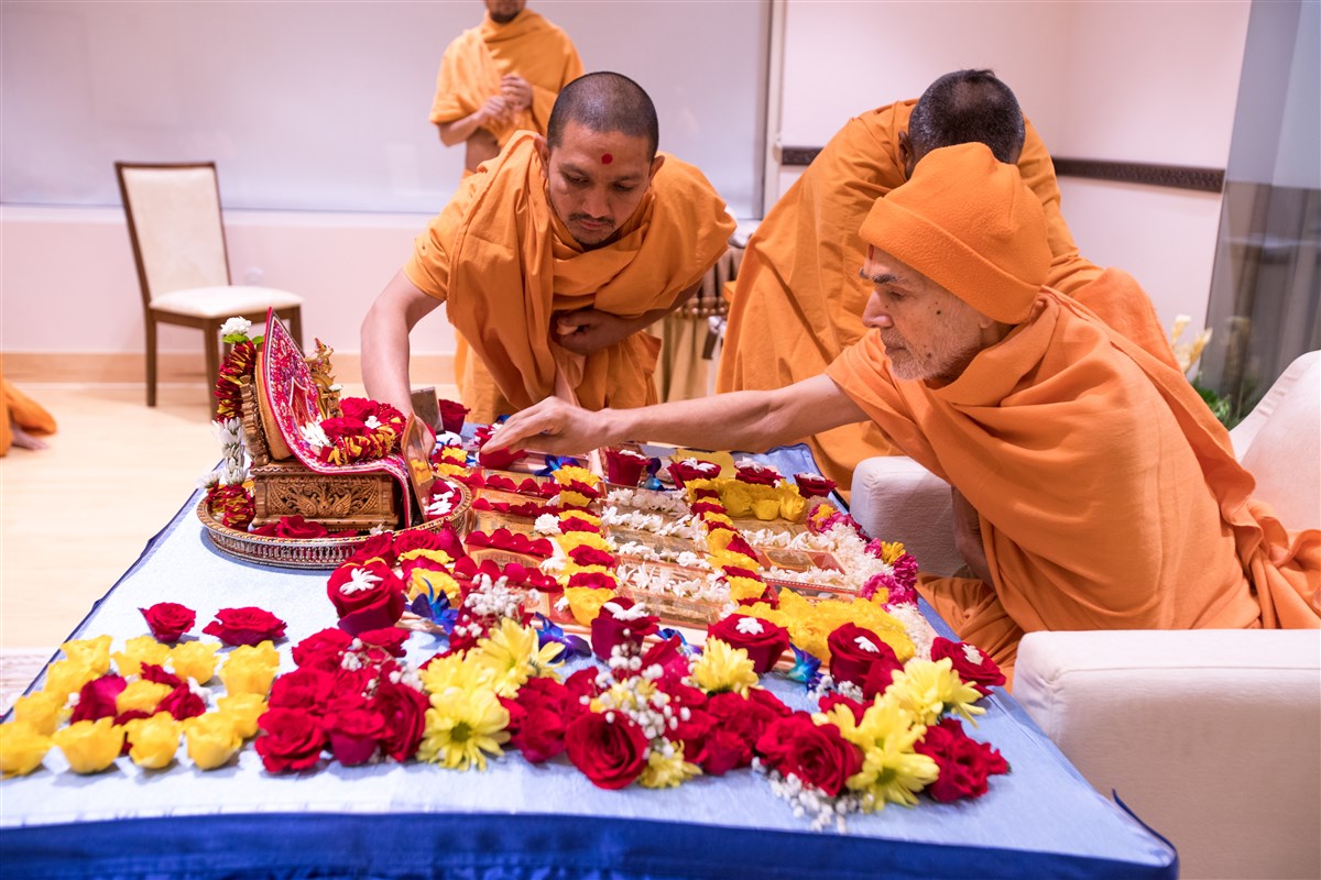 Swamishri arranges flowers surrounding the murtis in his puja