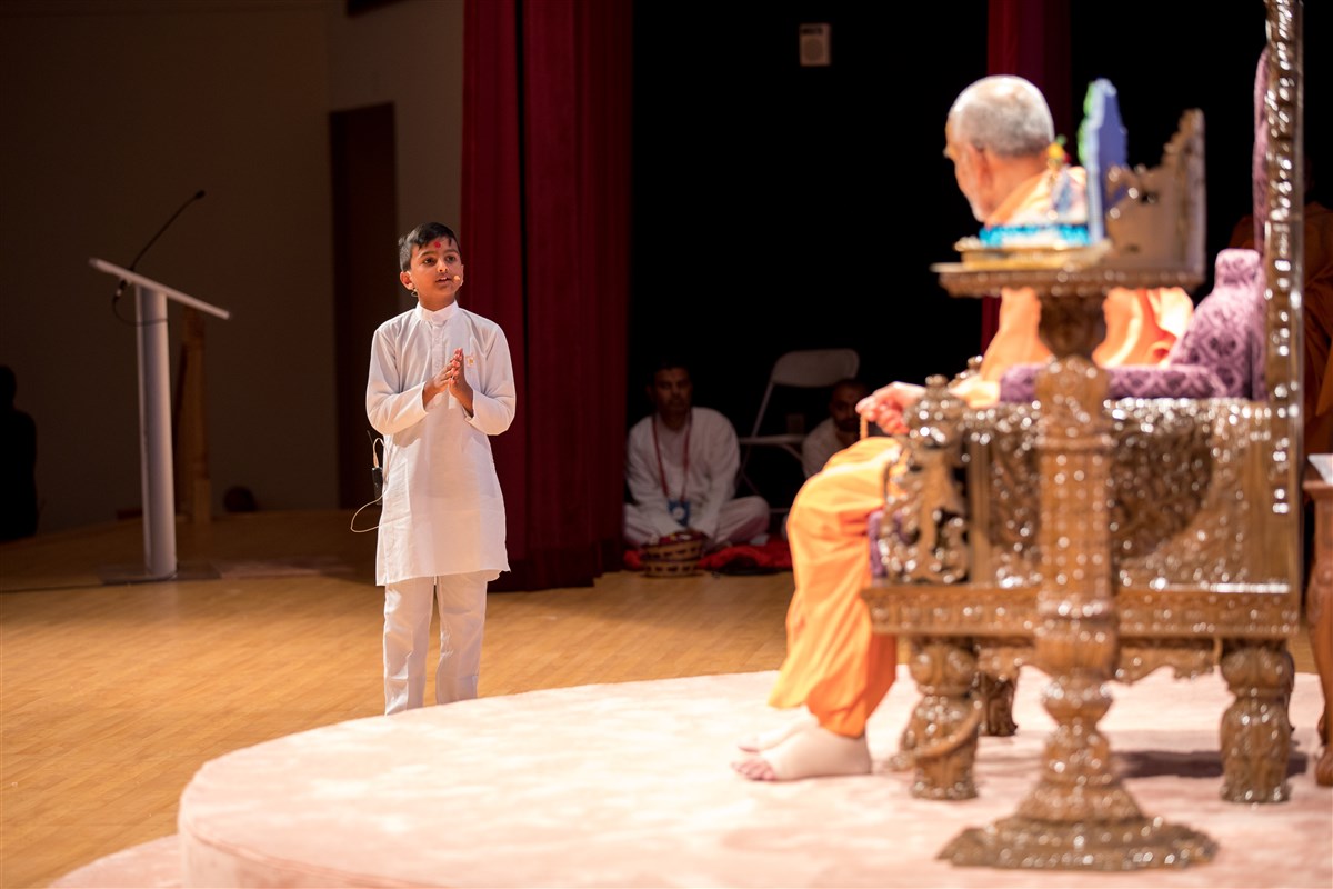 A child interacts with Swamishri to welcome him to North America