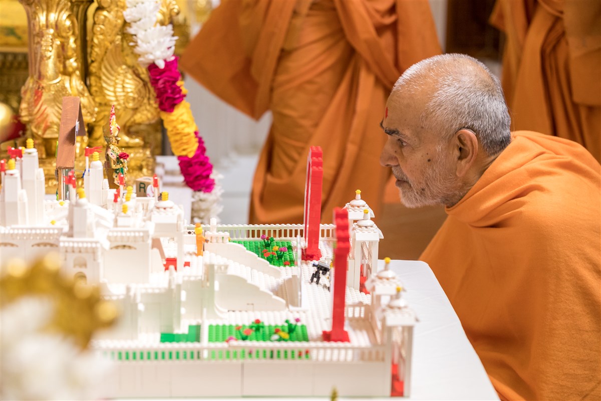 Swamishri engrossed in viewing a model of the Mandir made by a child